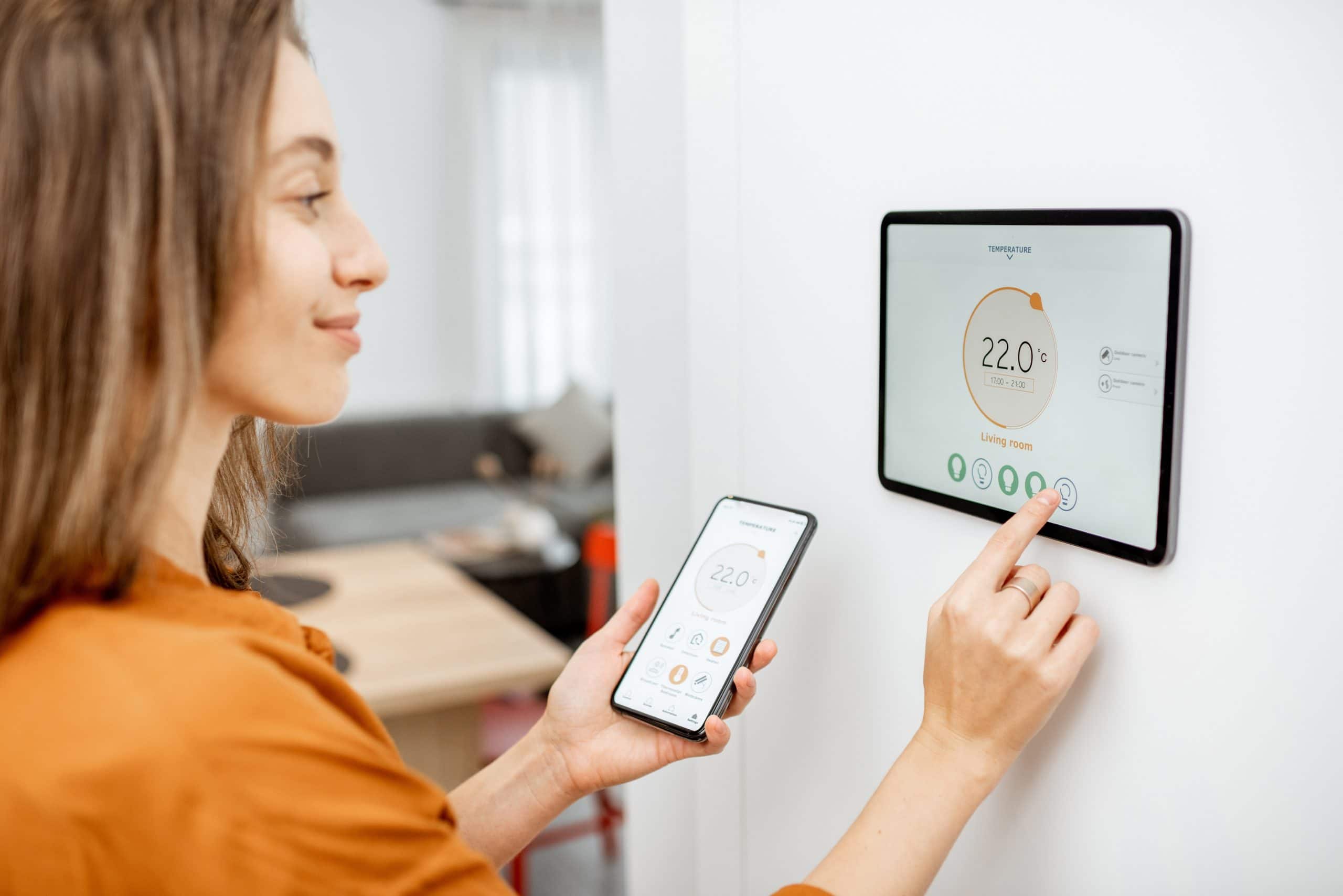 Woman Controlling Heating With A Smart Devices Cghxaml Scaled