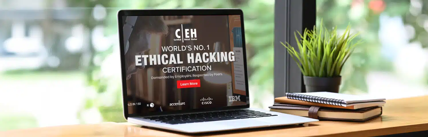 Laptop On A Desk Displaying An Advertisement For Ec Council’s Certified Ethical Hacker (ceh) Certification, With Company Logos Like Accenture, Cisco, And Ibm Visible On Screen